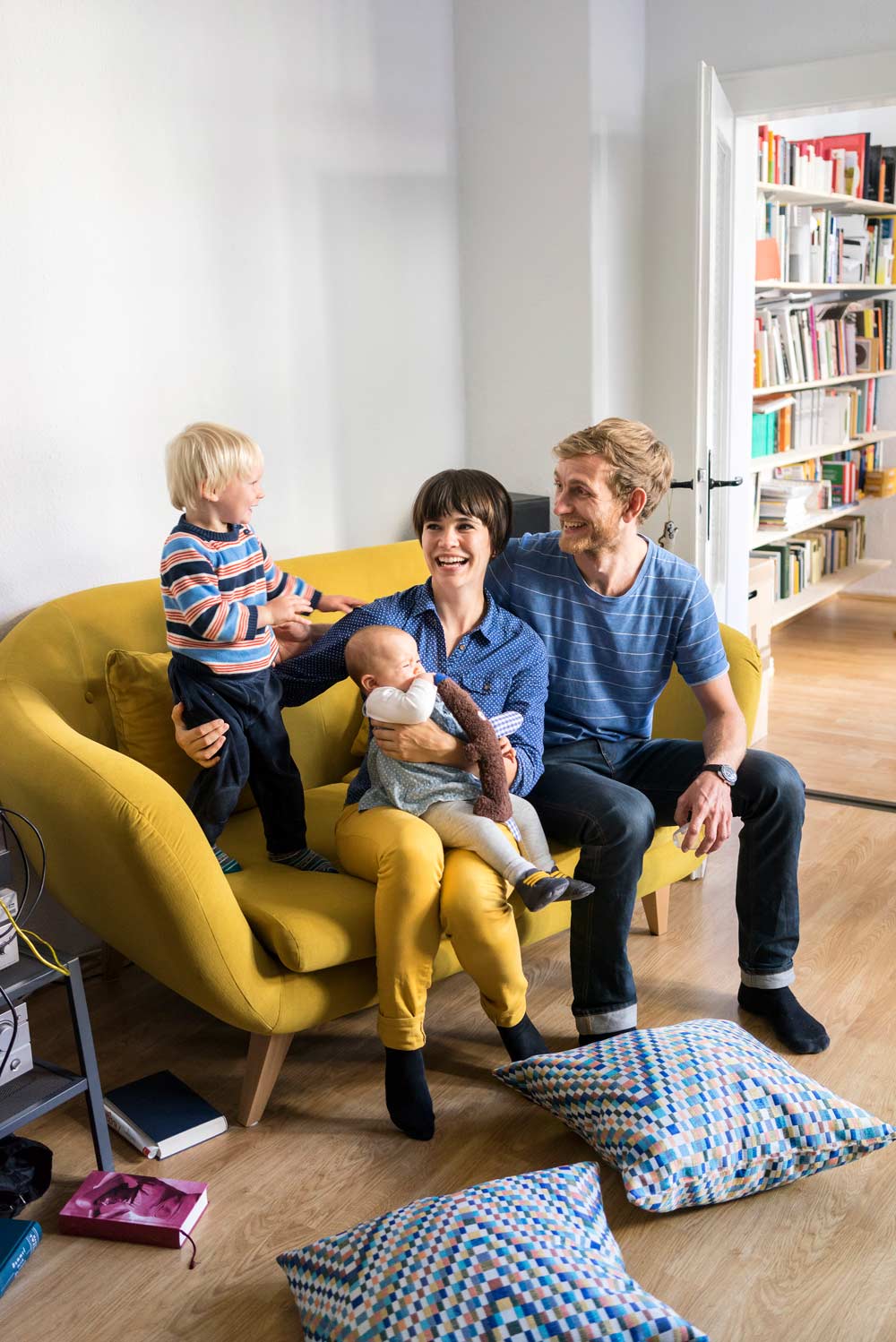 En familj på fyra personer leker och skrattar i sitt hem.
